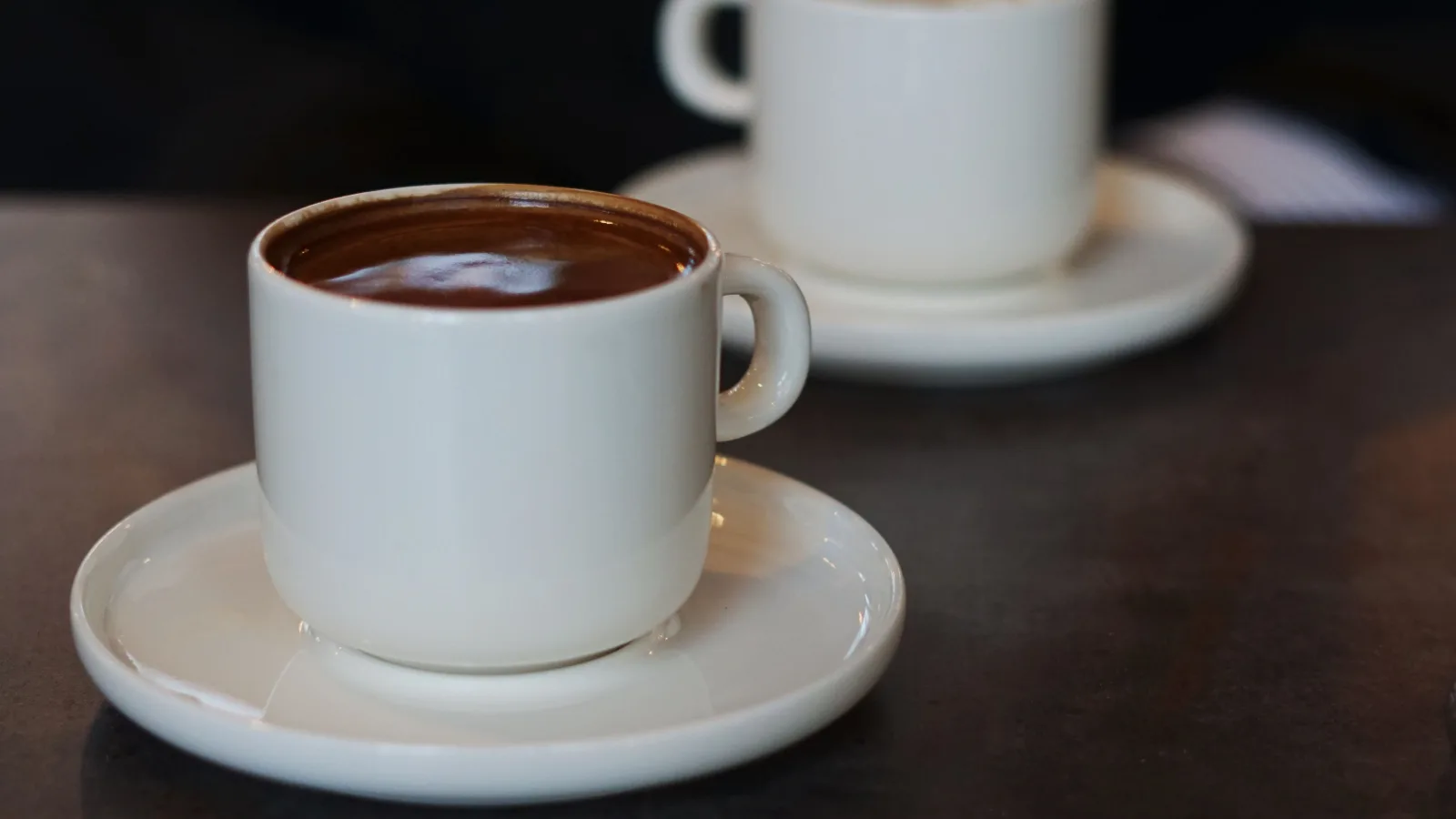 Two mugs on a kitchen table, one full and one nearly empty