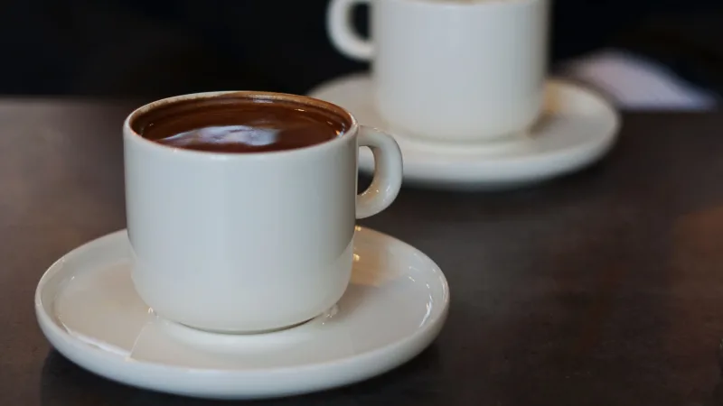 Two mugs on a kitchen table, one full and one nearly empty